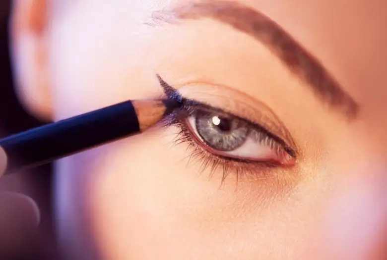 a woman applying eyeliner