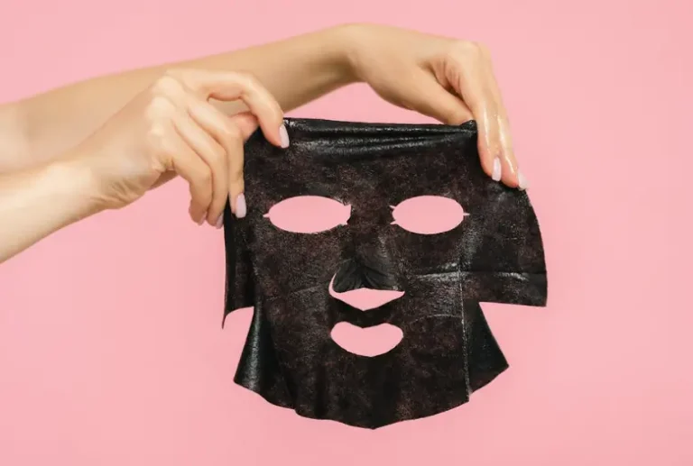 Two hands holding a black Korean charcoal face mask for skin beauty