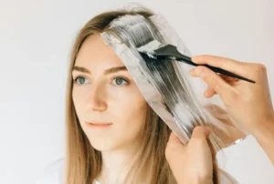 A woman applying blonde box dye to her bleached hair