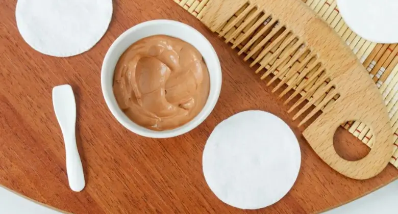 Bowl of bentonite clay paste with a comb and applying spoon nearby