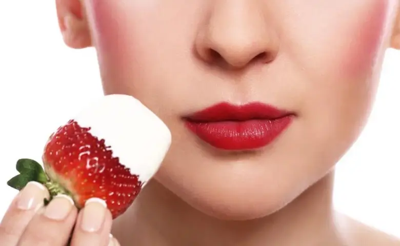 Girl holding a strawberry close to her face