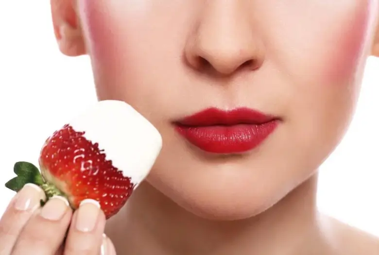 Girl holding a strawberry near her lips for skin benefits