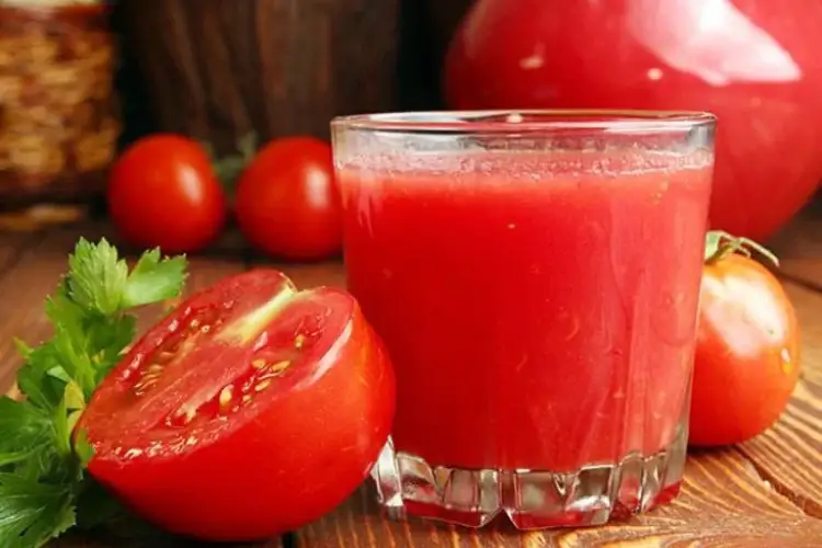 Whole tomato, sliced tomato, and a glass of tomato juice used for skin brightening